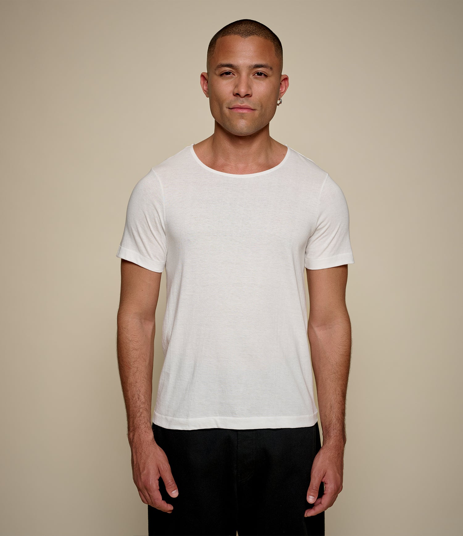 Man wearing a white loopwheeled t-shirt with wide round-neck against a beige background