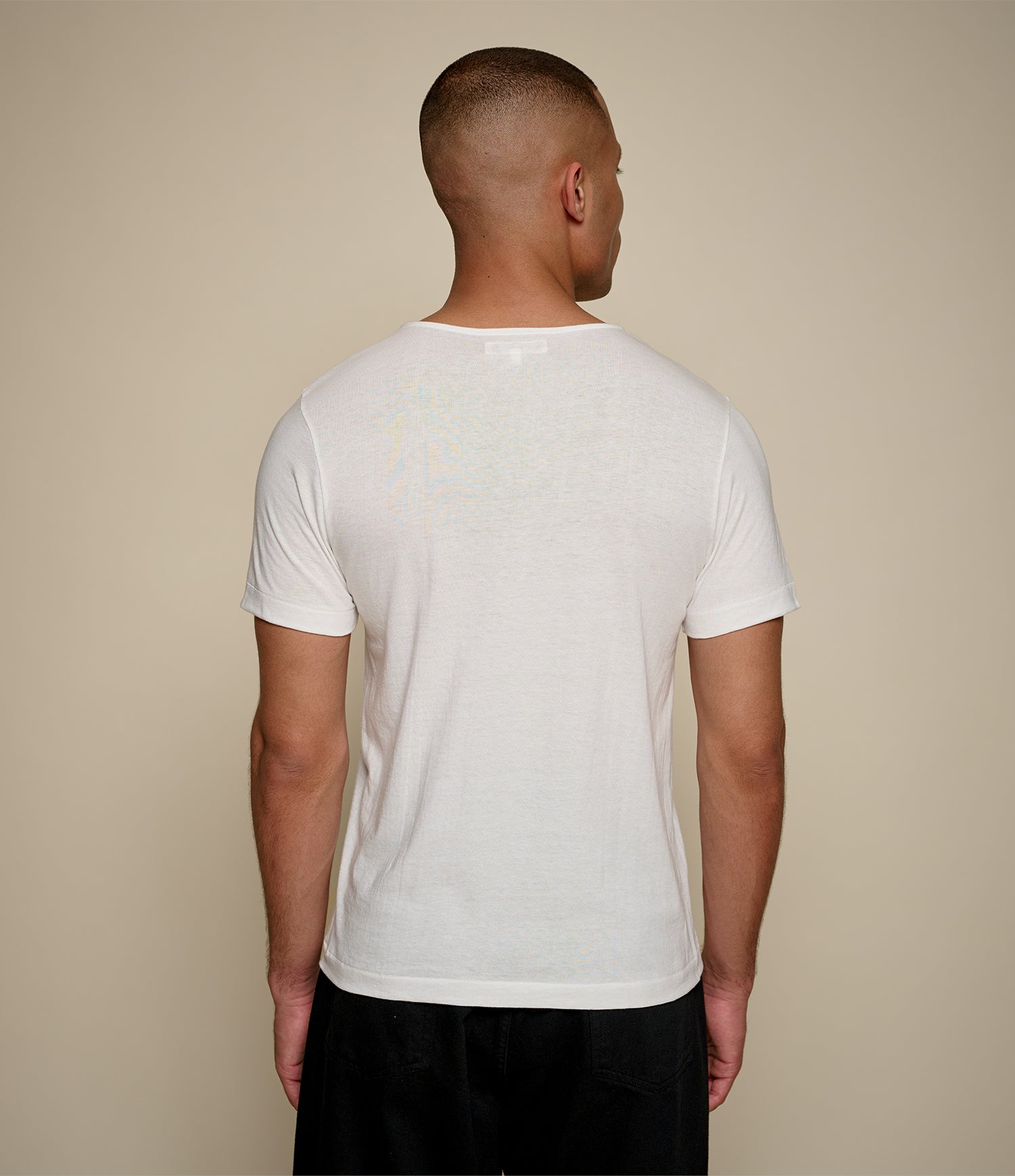 Man wearing a plain white loopwheeled t-shirt against a beige background
