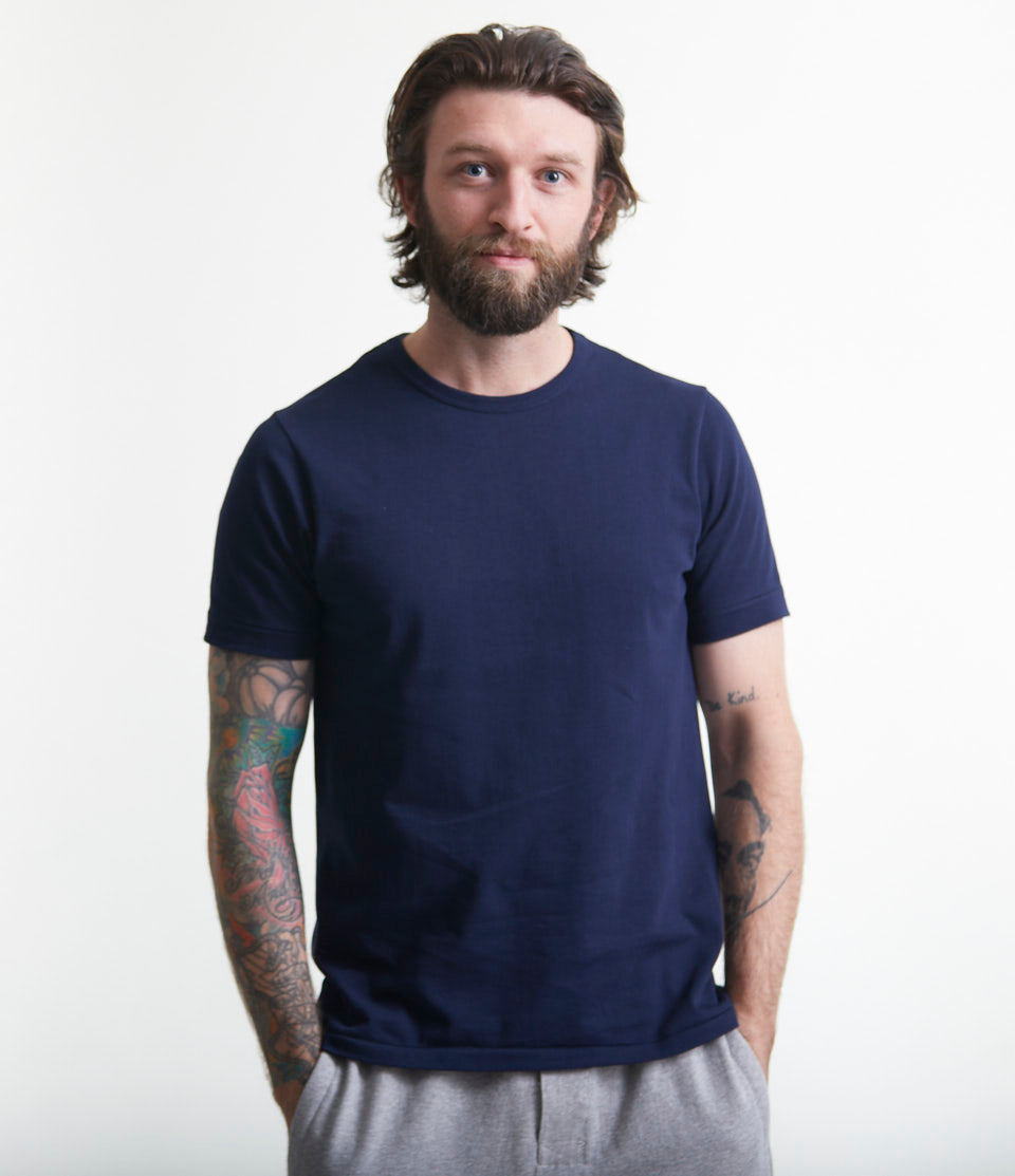 A man wearing a navy blue loopwheeled crew-neck T-shirt with short sleeves.