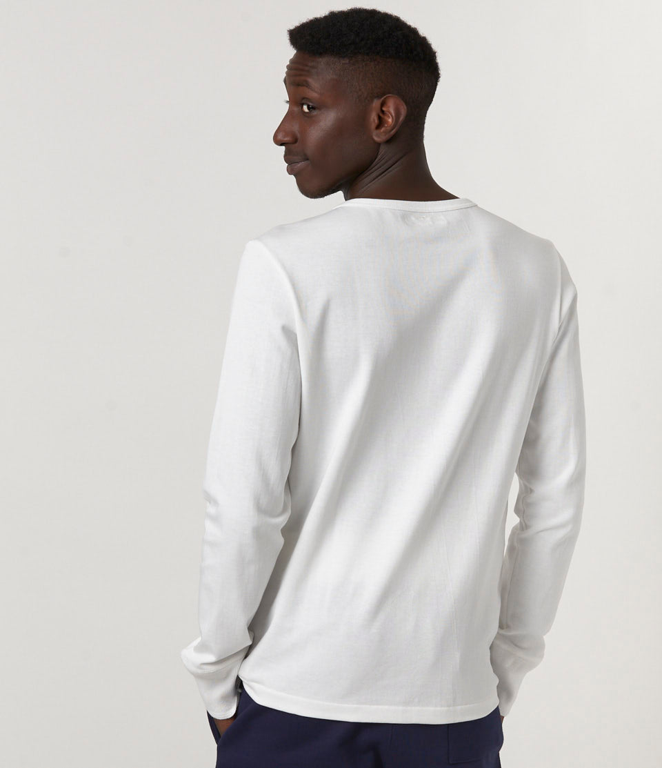 Person wearing a white long-sleeve shirt against a plain background