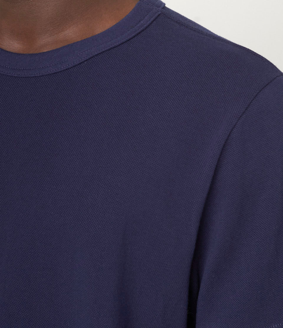 Close-up of a navy blue pikée t-shirt on a plain background