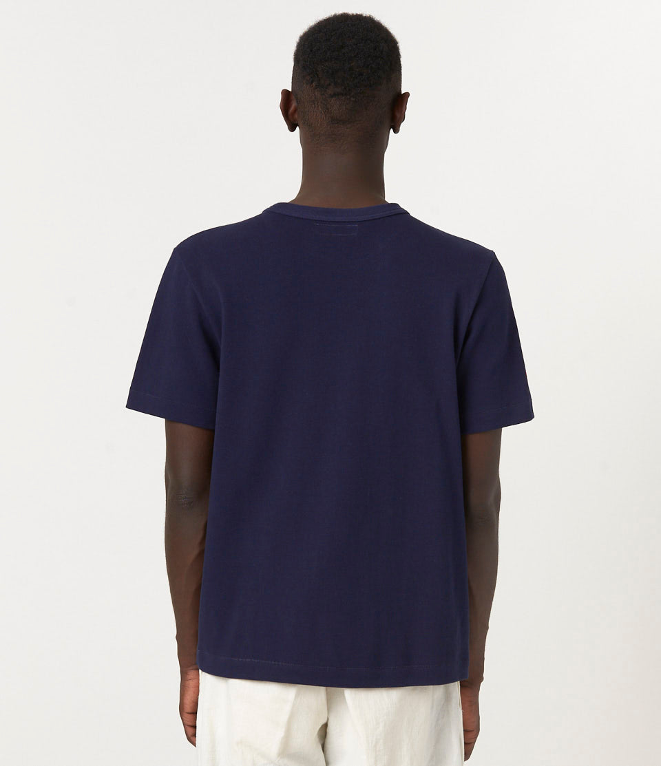 Person wearing a navy blue pikée t-shirt on a white background