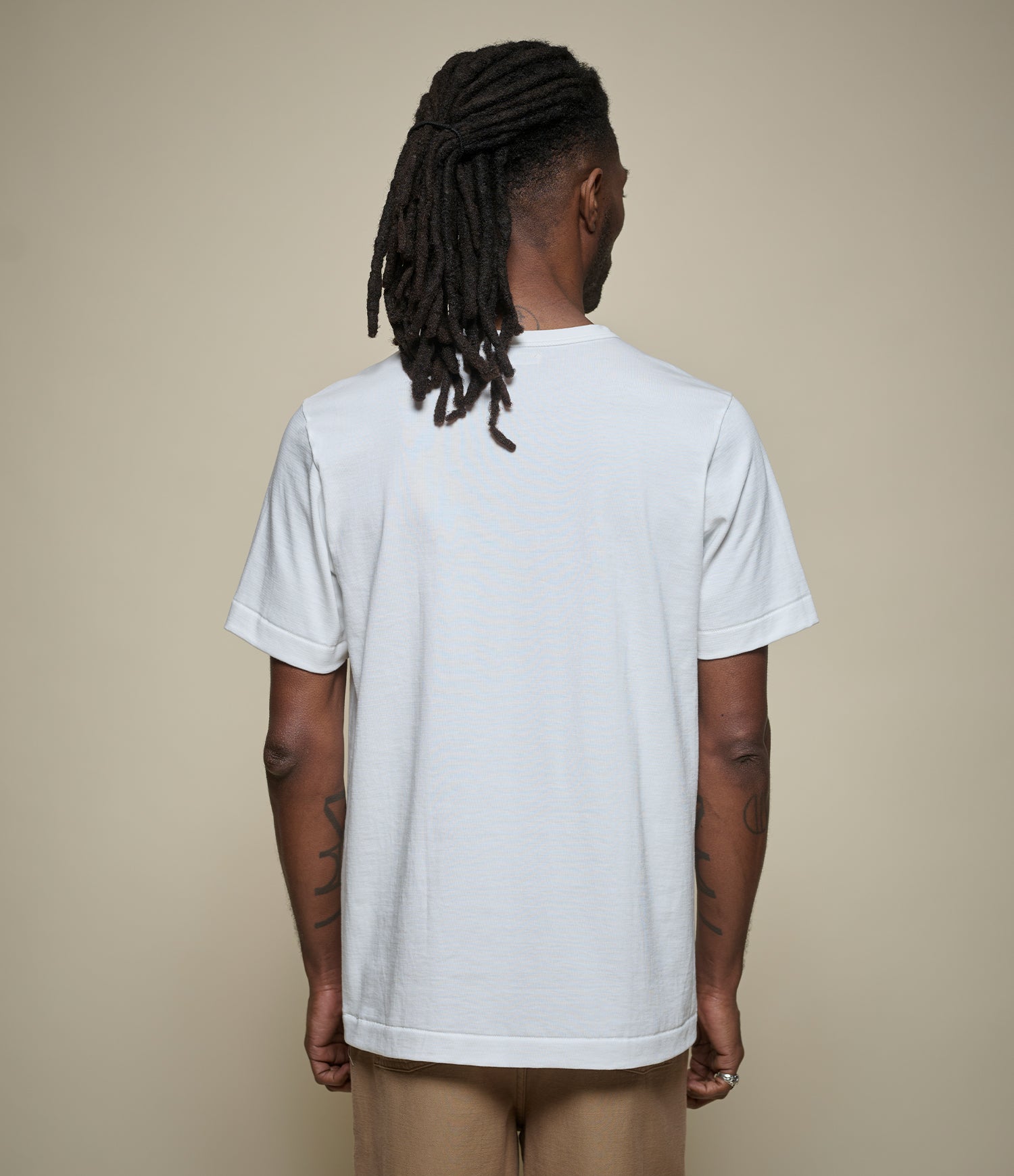 Person wearing a plain white t-shirt against a beige background