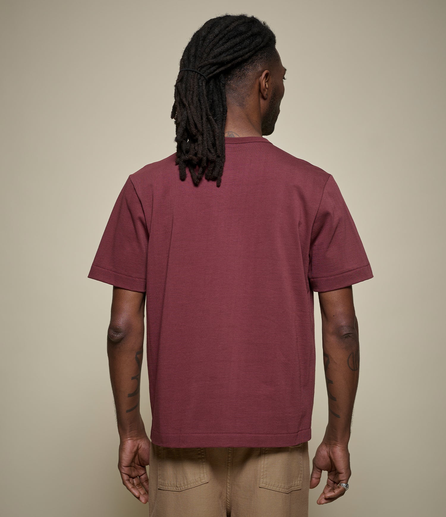 Person wearing a burgundy cropped t-shirt against a beige background