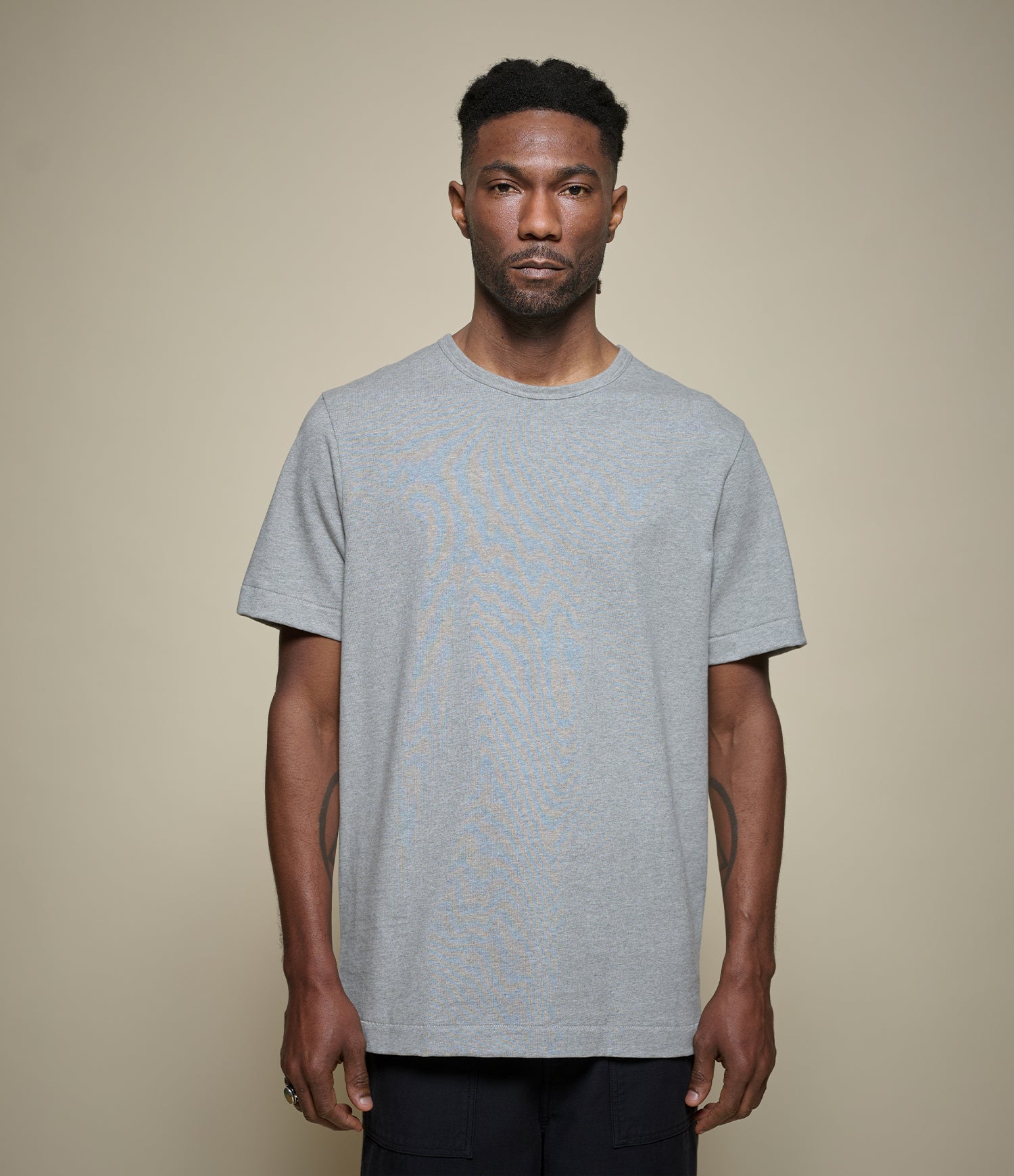 Man wearing a gray crew neck t-shirt against a beige background