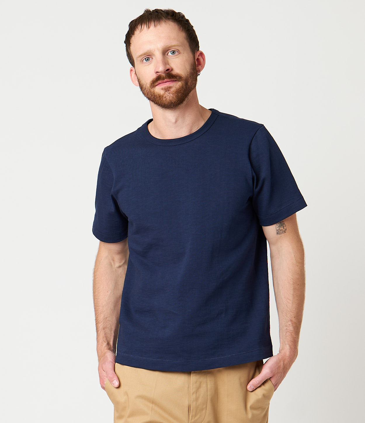 A person wearing a navy blue loopwheeled T-shirt with a relaxed fit and a ribbed crew neck.