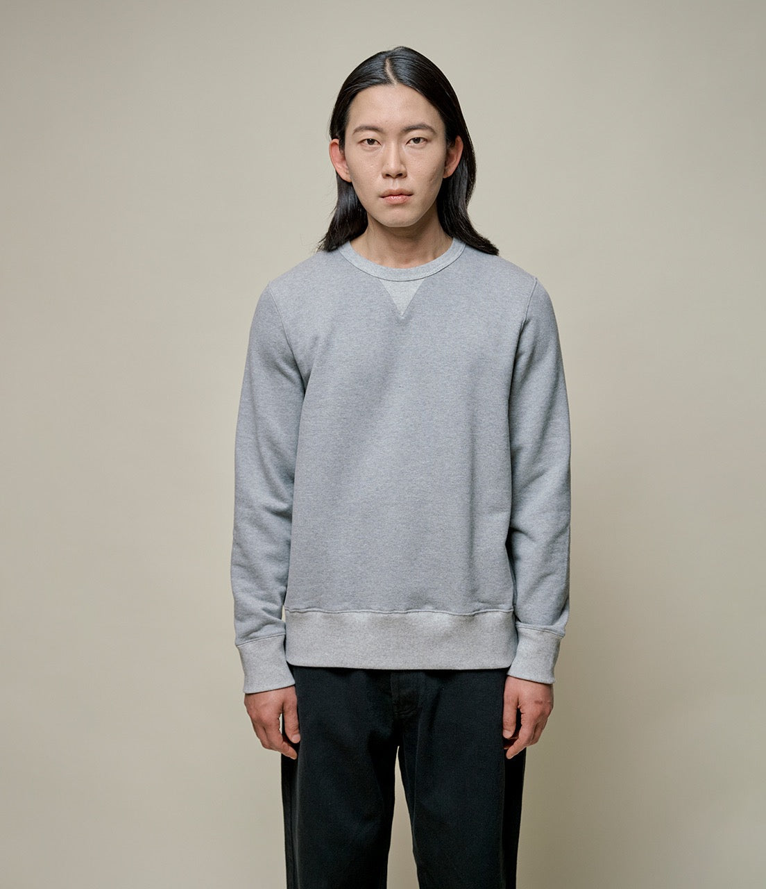 A person wearing a gray fleece sweatshirt with a round neckline and long sleeves.