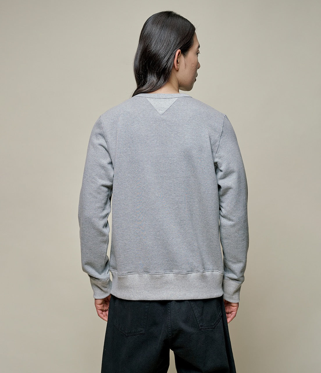 Person wearing a gray sweatshirt against a plain background