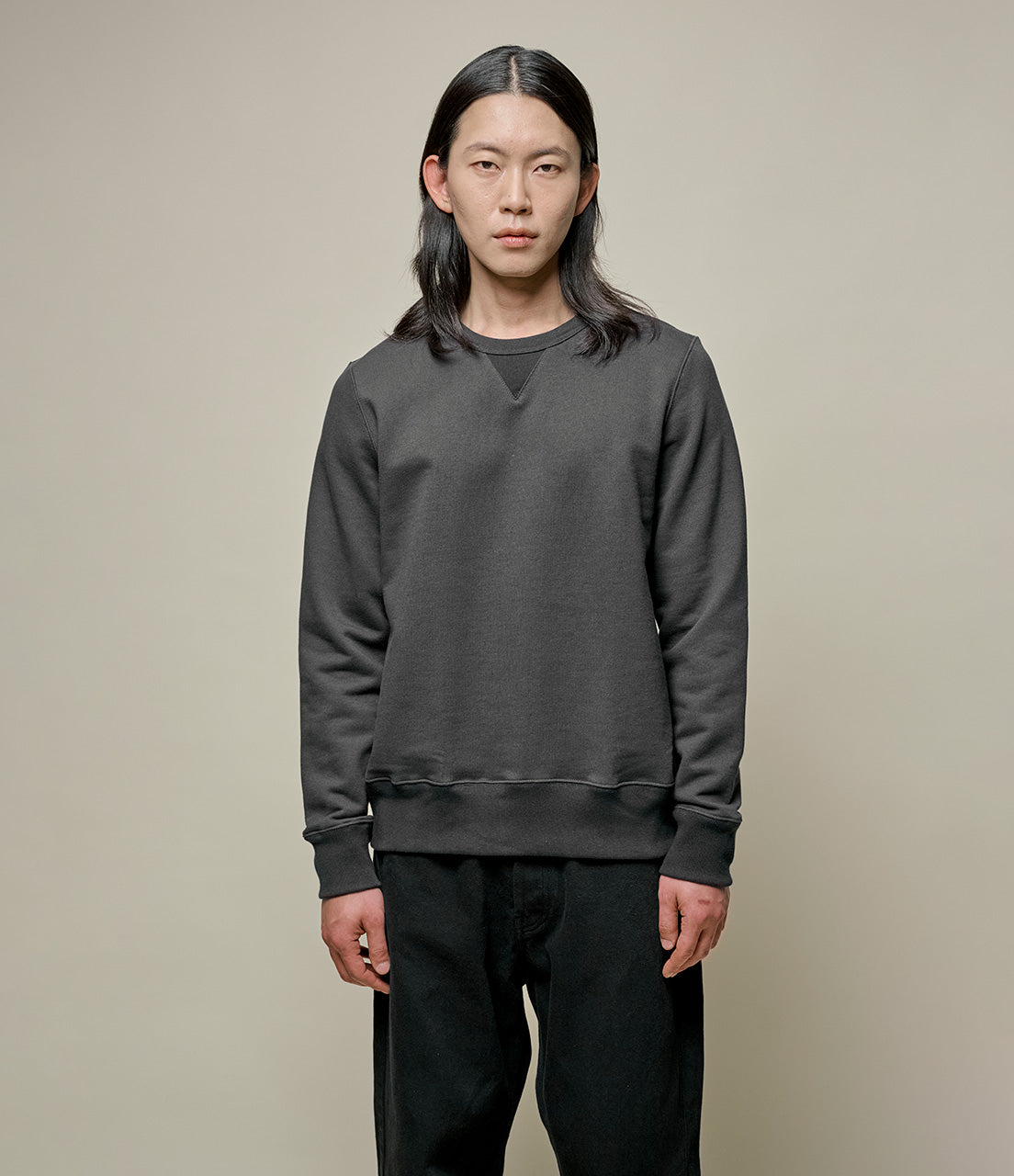 A person wearing a dark gray fleece sweatshirt with a round neckline and long sleeves.