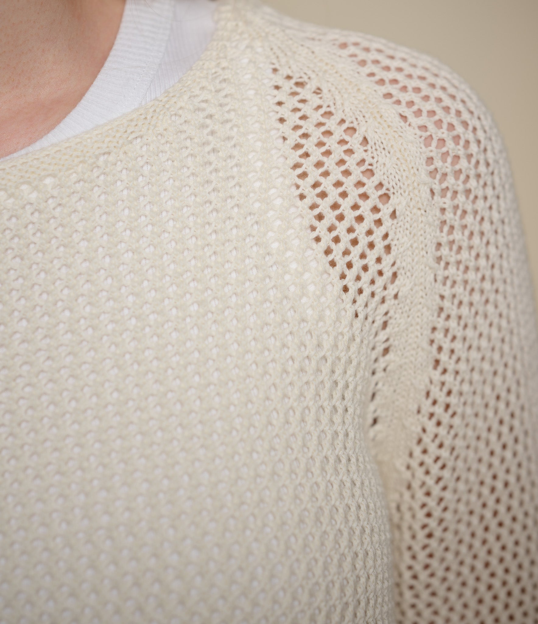 Close-up of a beige knitted sweater with a textured pattern.