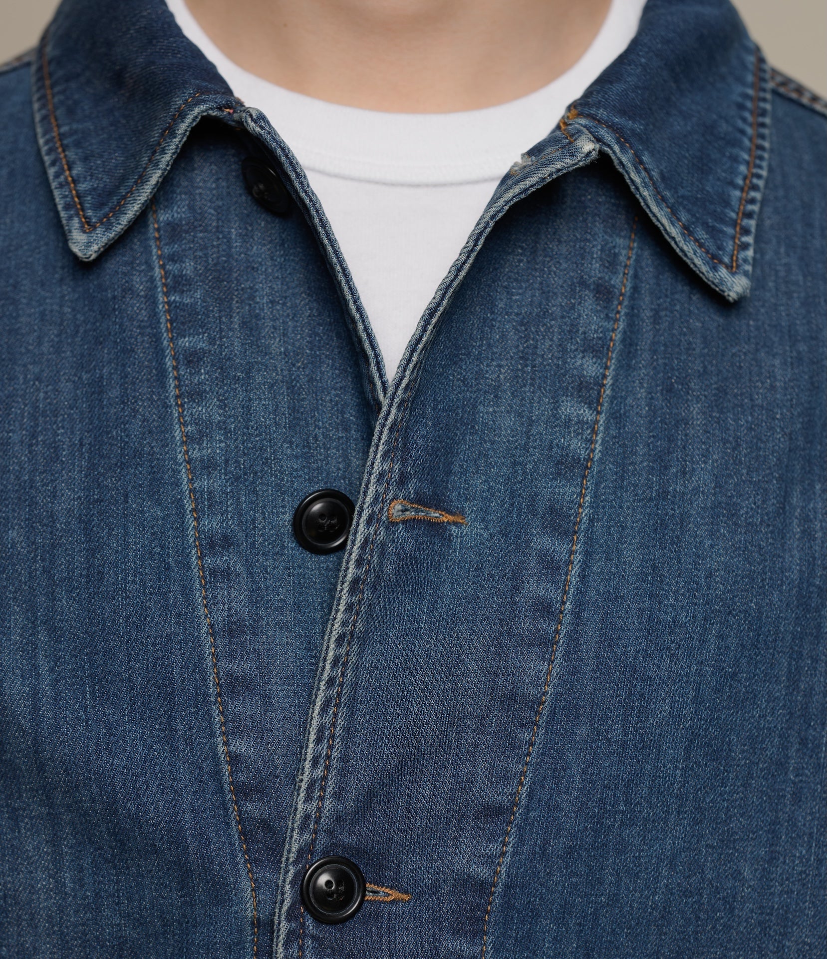 Close-up of a blue denim jacket with buttons on a neutral background