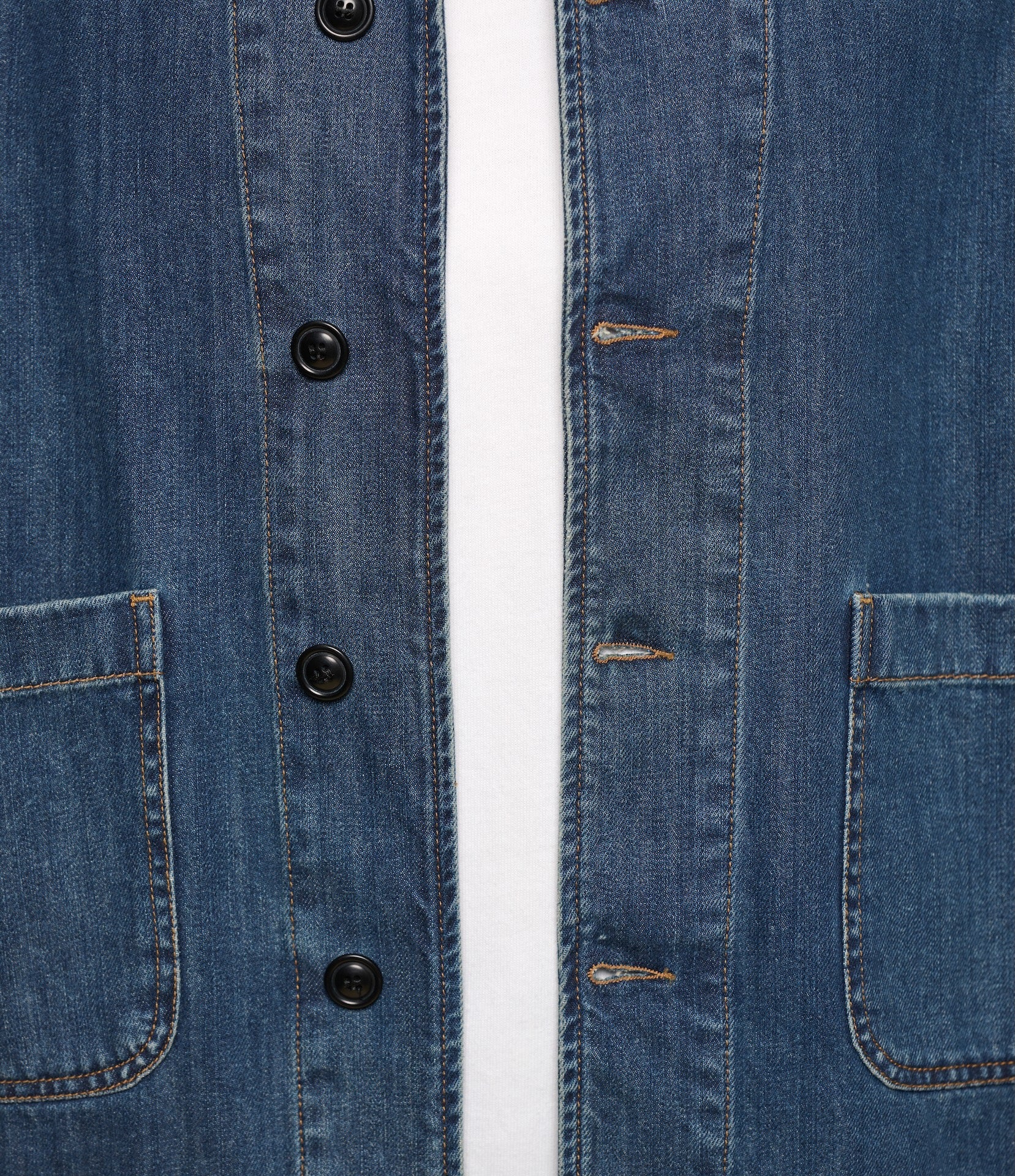 Close-up of a blue denim jacket with buttons and a white background