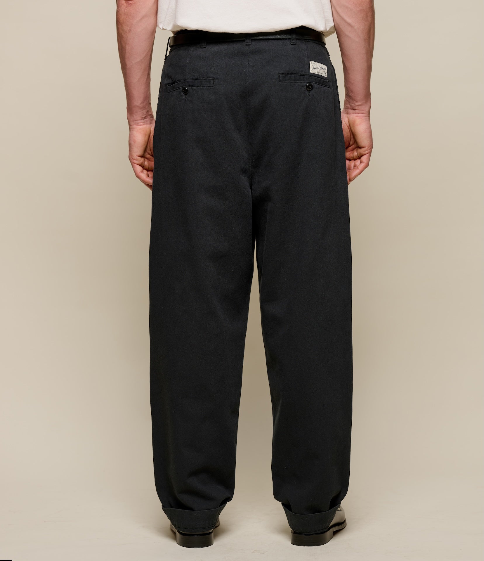 Person wearing black pants on a beige background