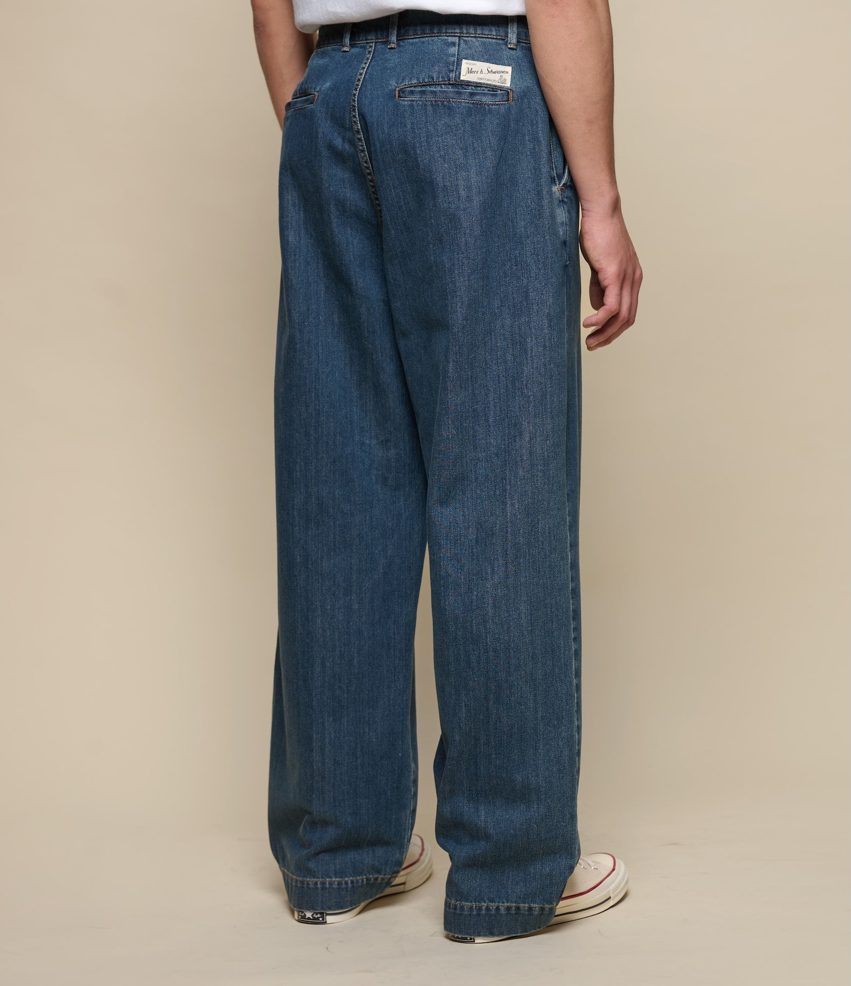 Person wearing blue jeans on a beige background