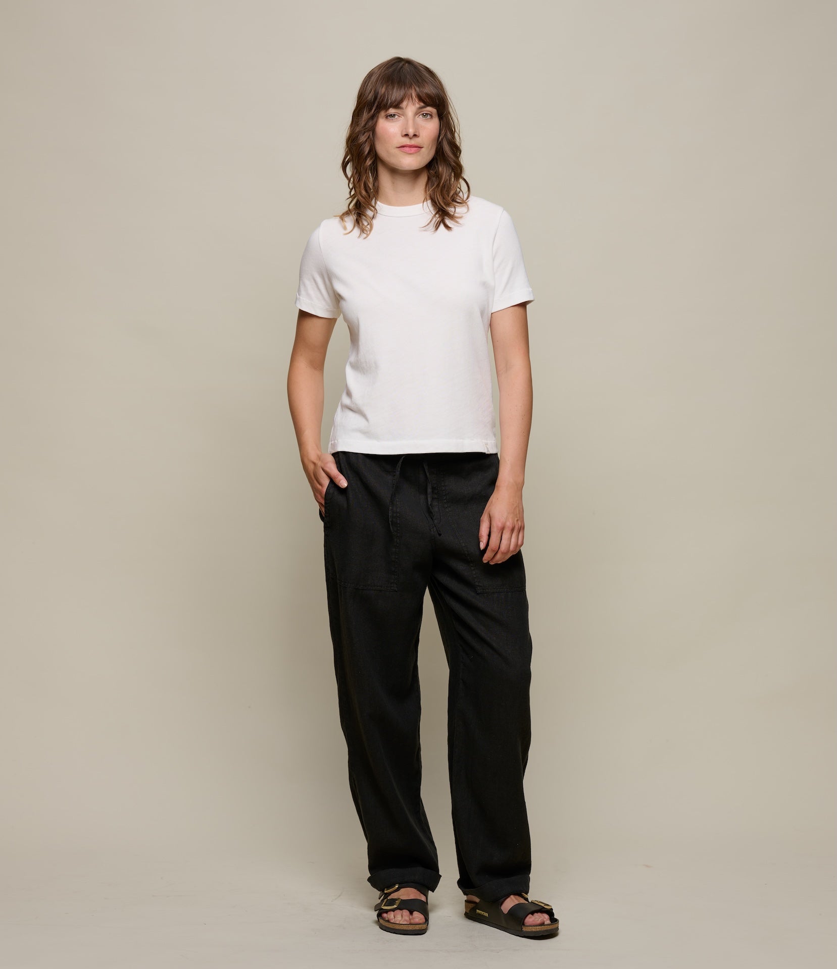 Person wearing a white t-shirt and black pants against a plain background