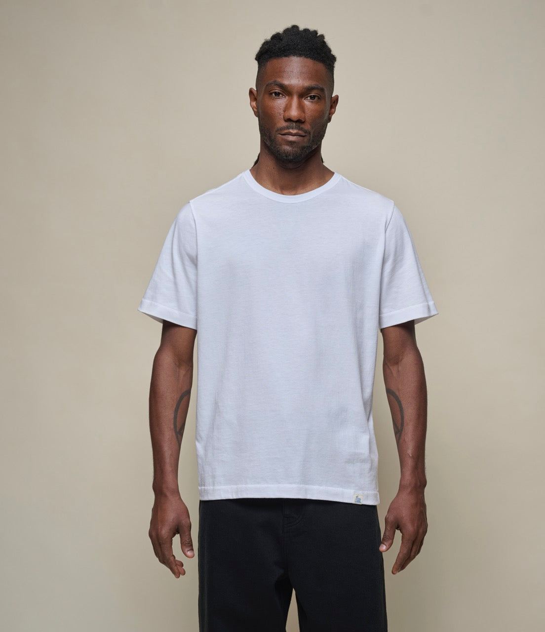 Man wearing a plain white pima cotton t-shirt against a beige background