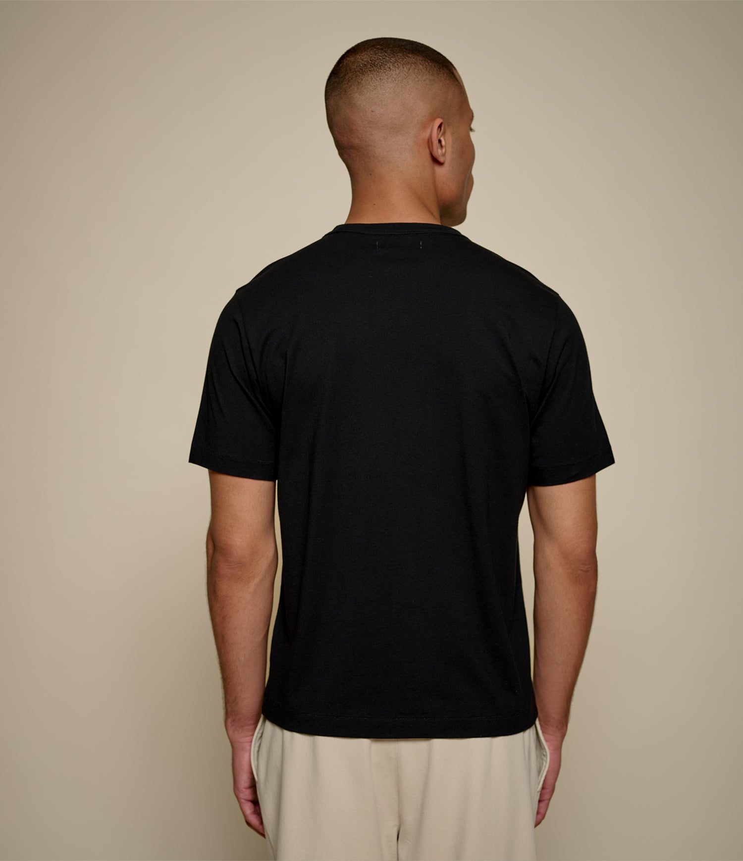 Man wearing a black t-shirt against a beige background