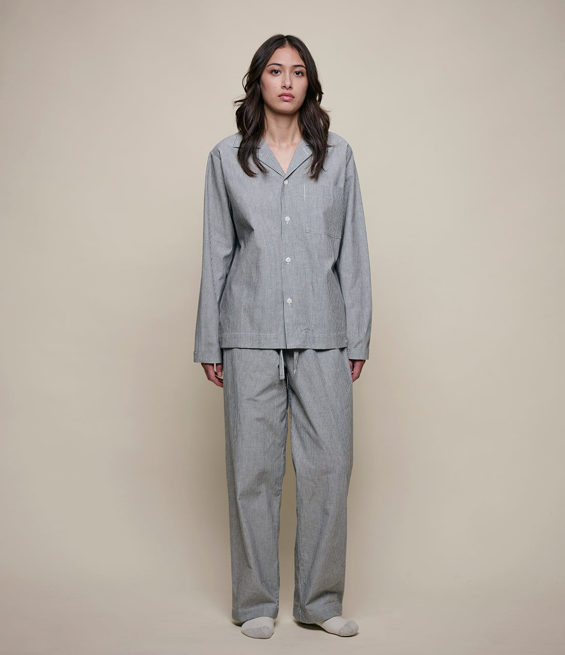 Woman wearing gray checkered pajamas against a beige background