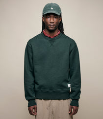 Man wearing a green sweatshirt and cap against a beige background