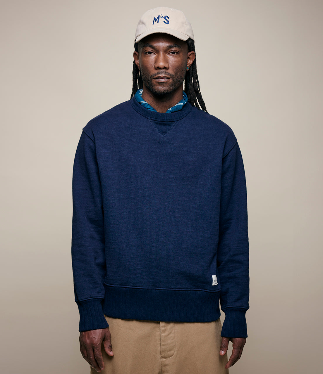 A person wearing a navy blue fleece cotton sweatshirt with a white cap featuring the letters 'MS' on the front.