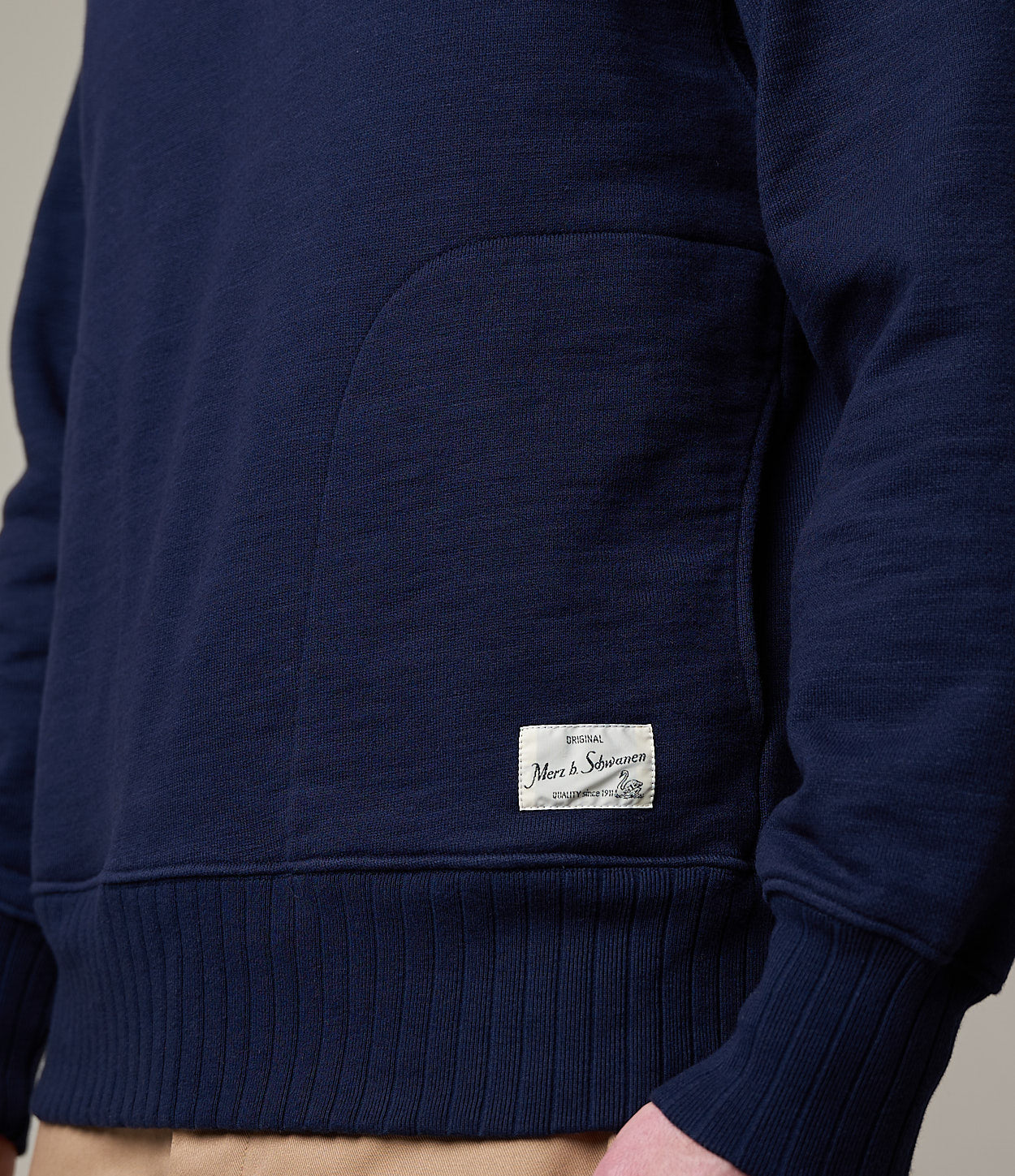 close up shot of navy hoodie with label on the pocket