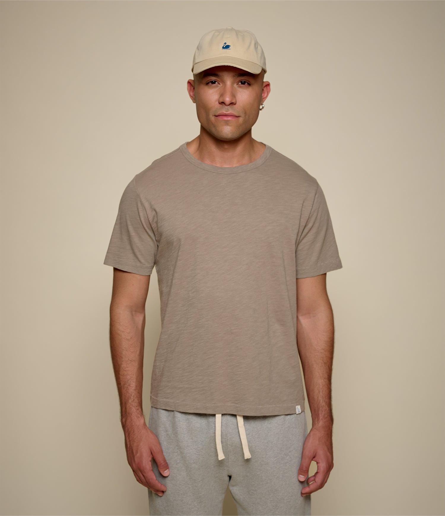 Man wearing a brown t-shirt and cap against a plain background