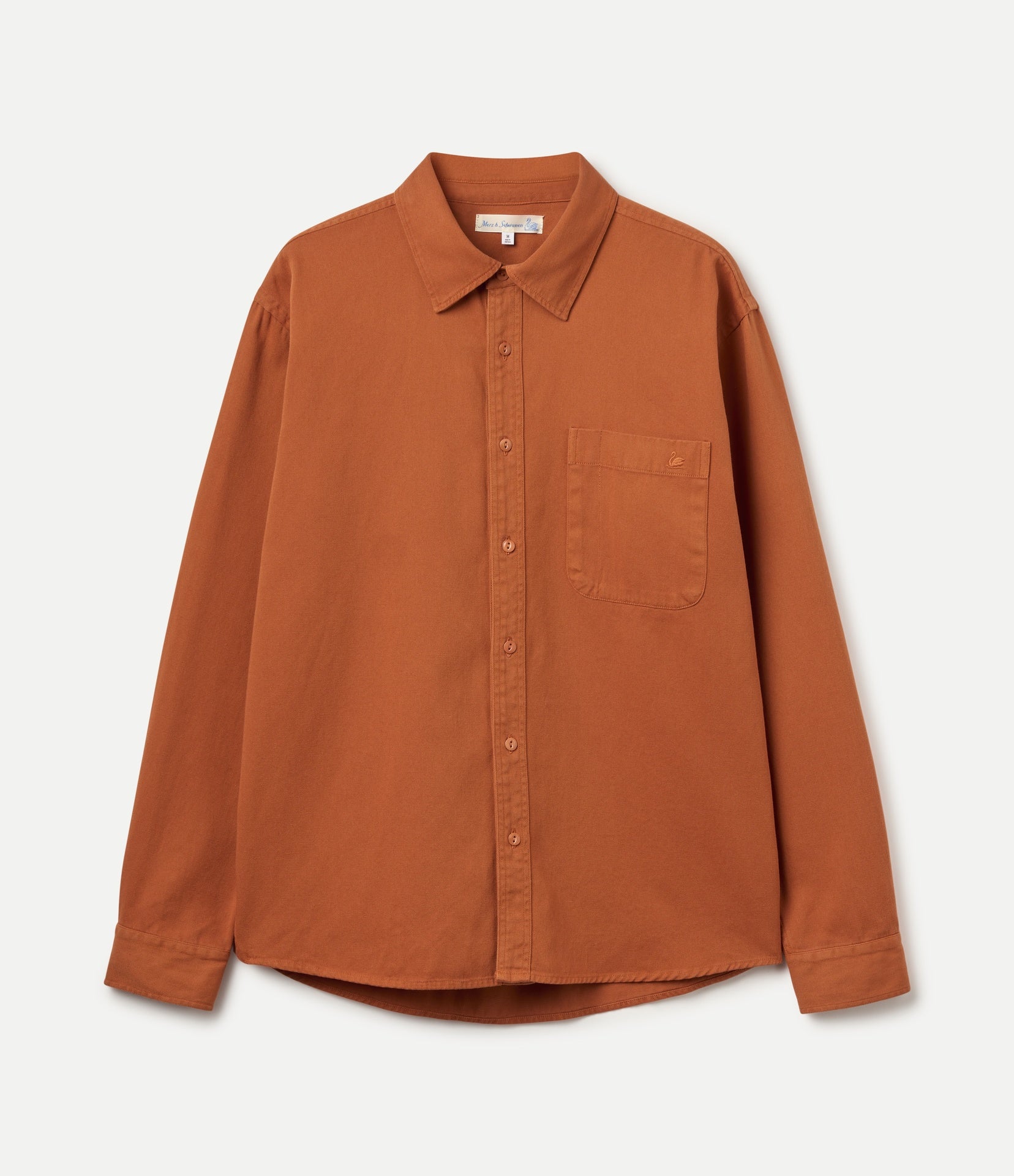 A rust-orange long-sleeve button-up shirt with a single chest pocket, laid flat against a light off-white background.