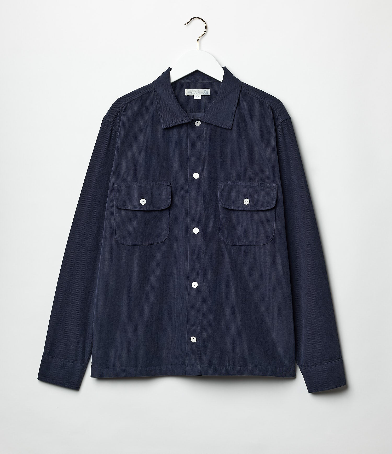 A long sleeve navy blue corduroy shirt with a collar, buttons, and two front pockets, displayed on a hanger against a white background.